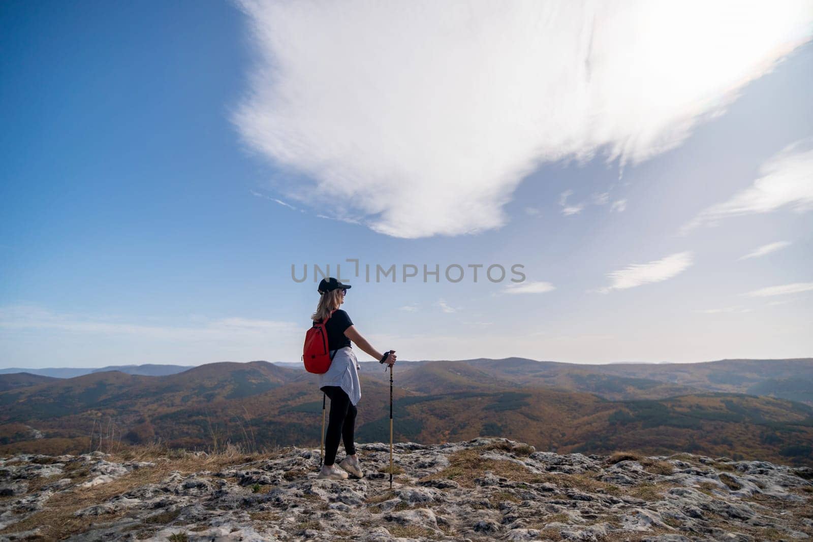 woman backpack on mountain peak looking in beautiful mountain valley in autumn. Landscape with sporty young woman, blu sky in fall. Hiking. Nature.