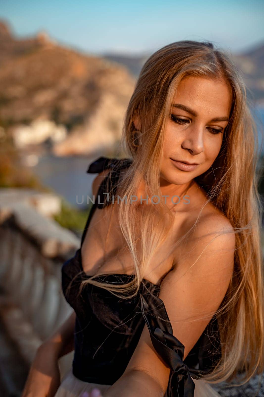 Blonde long hair, nature summer happy adult girl with long blond hair developing in the wind in nature. Dressed in a black top, white skirt