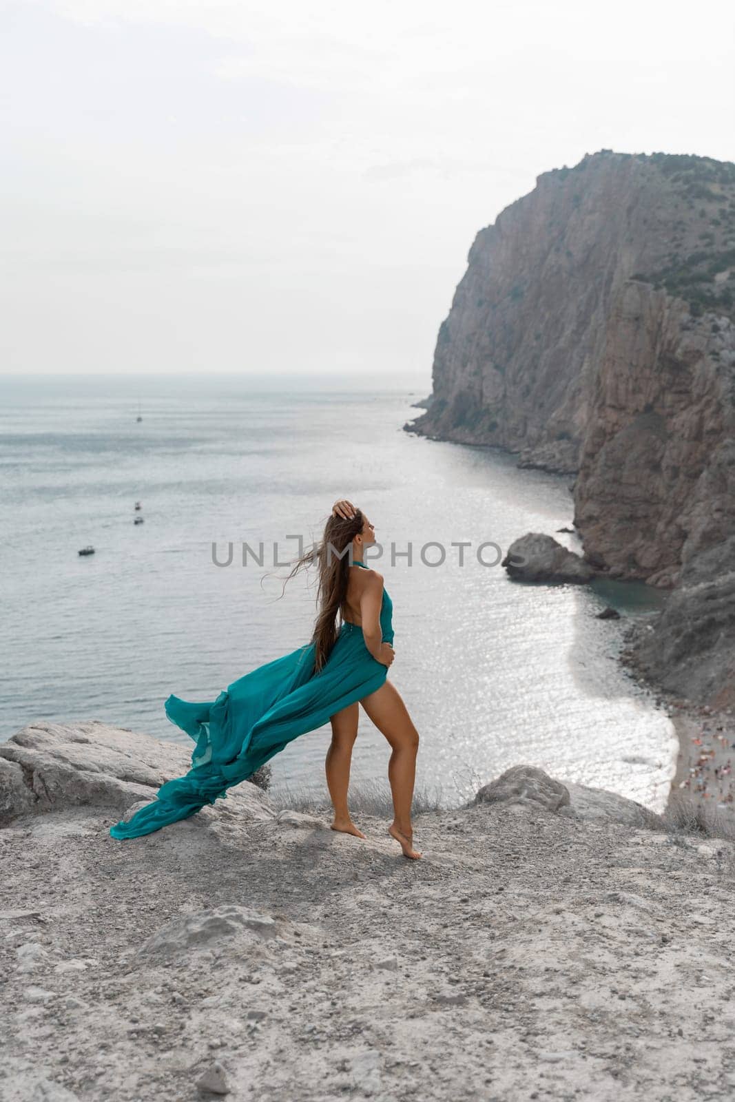 Woman sea green dress. Side view a happy woman with long hair in a long mint dress posing on a beach with calm sea bokeh lights on sunny day. Girl on the nature on blue sky background