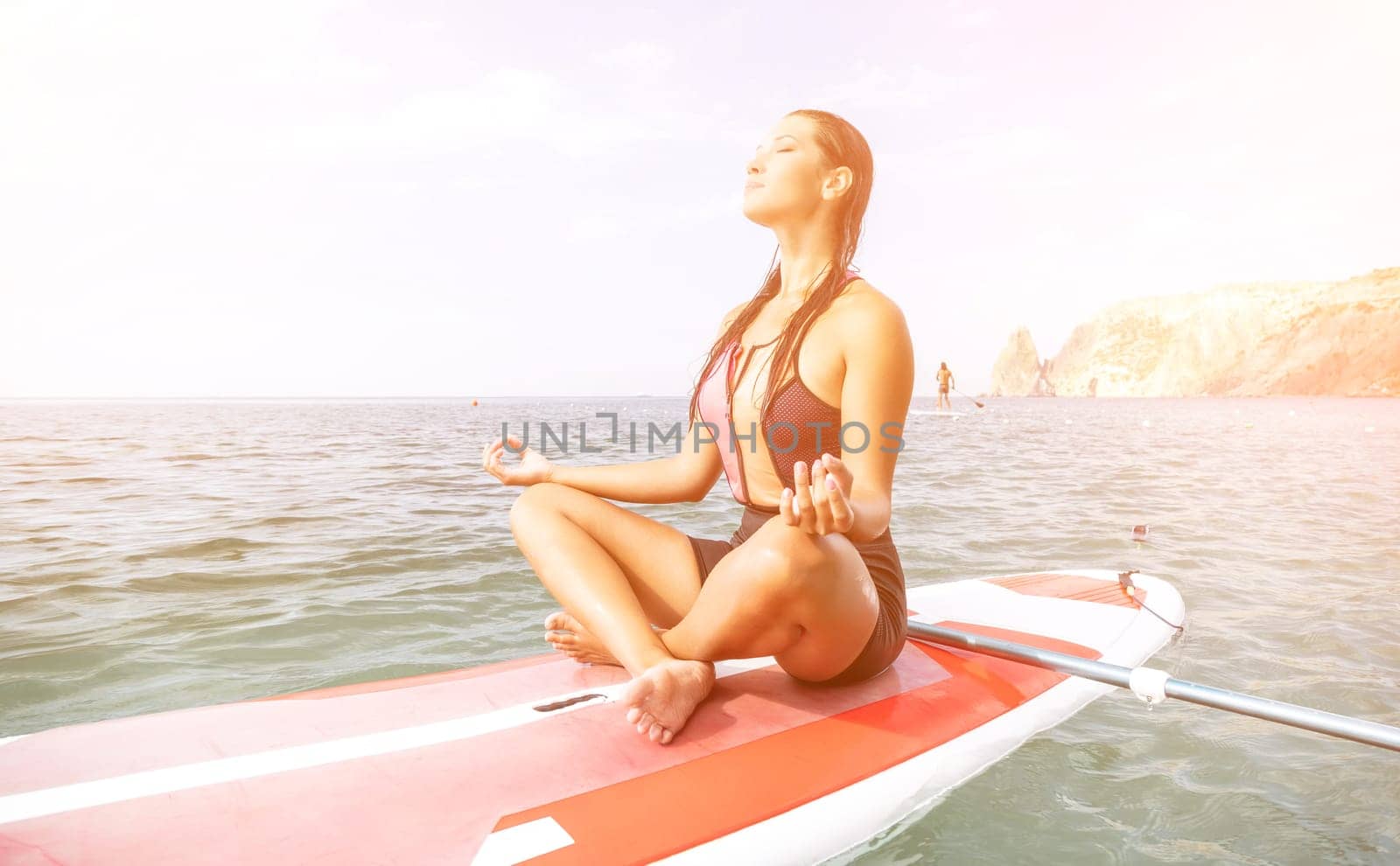 Woman sup yoga. Happy young sporty woman practising yoga pilates on paddle sup surfboard. Female stretching doing workout on sea water. Modern individual female outdoor summer sport activity