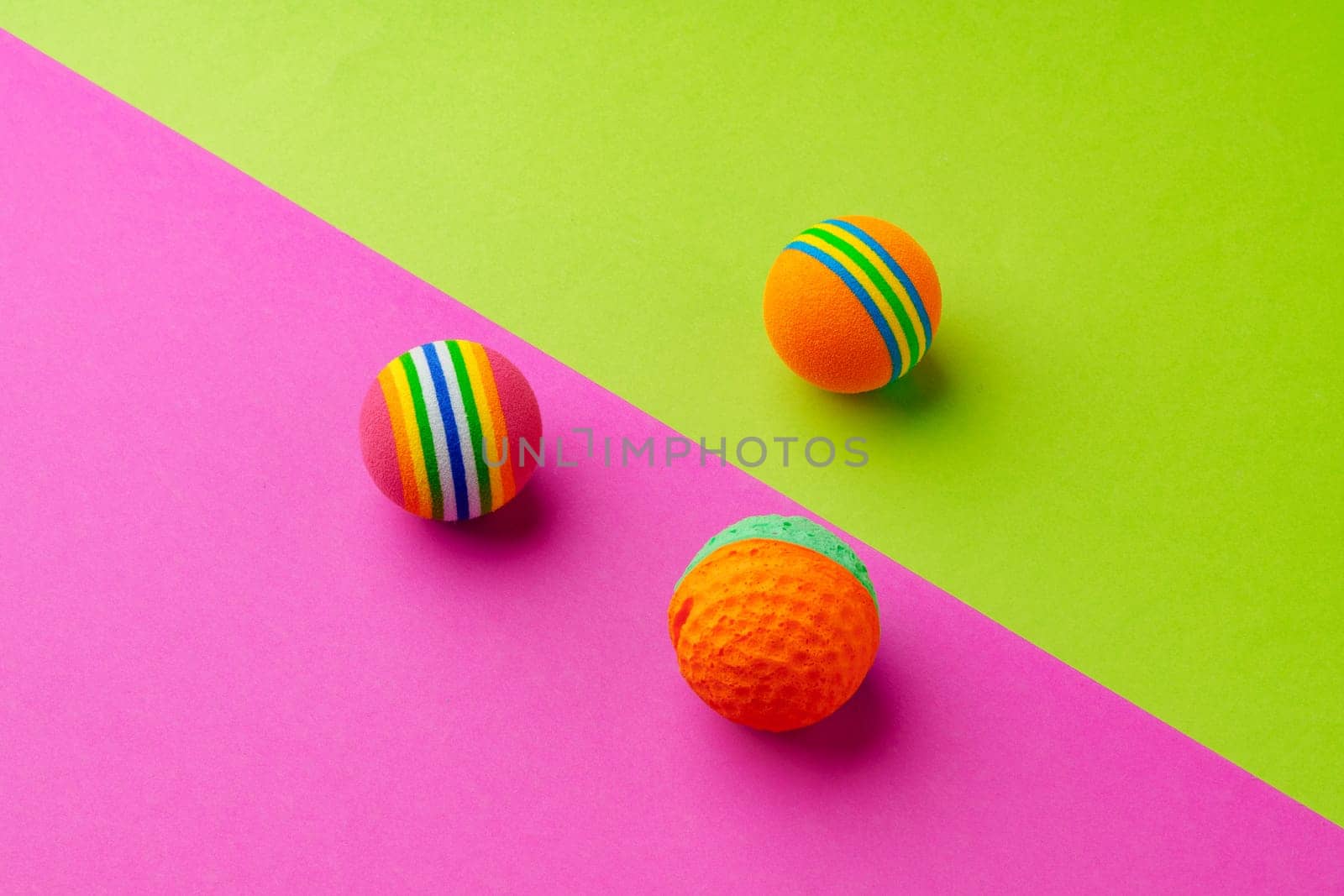 Pet toys balls on pink and green background studio shot top view