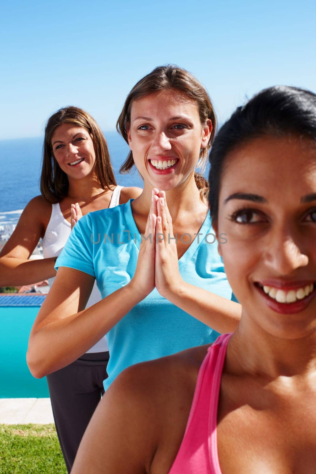 Ocean, yoga and namaste with group of women on grass together for fitness, exercise or mindfulness resort. Nature, relax and happy friends at outdoor holistic retreat for wellness, zen and sunshine.