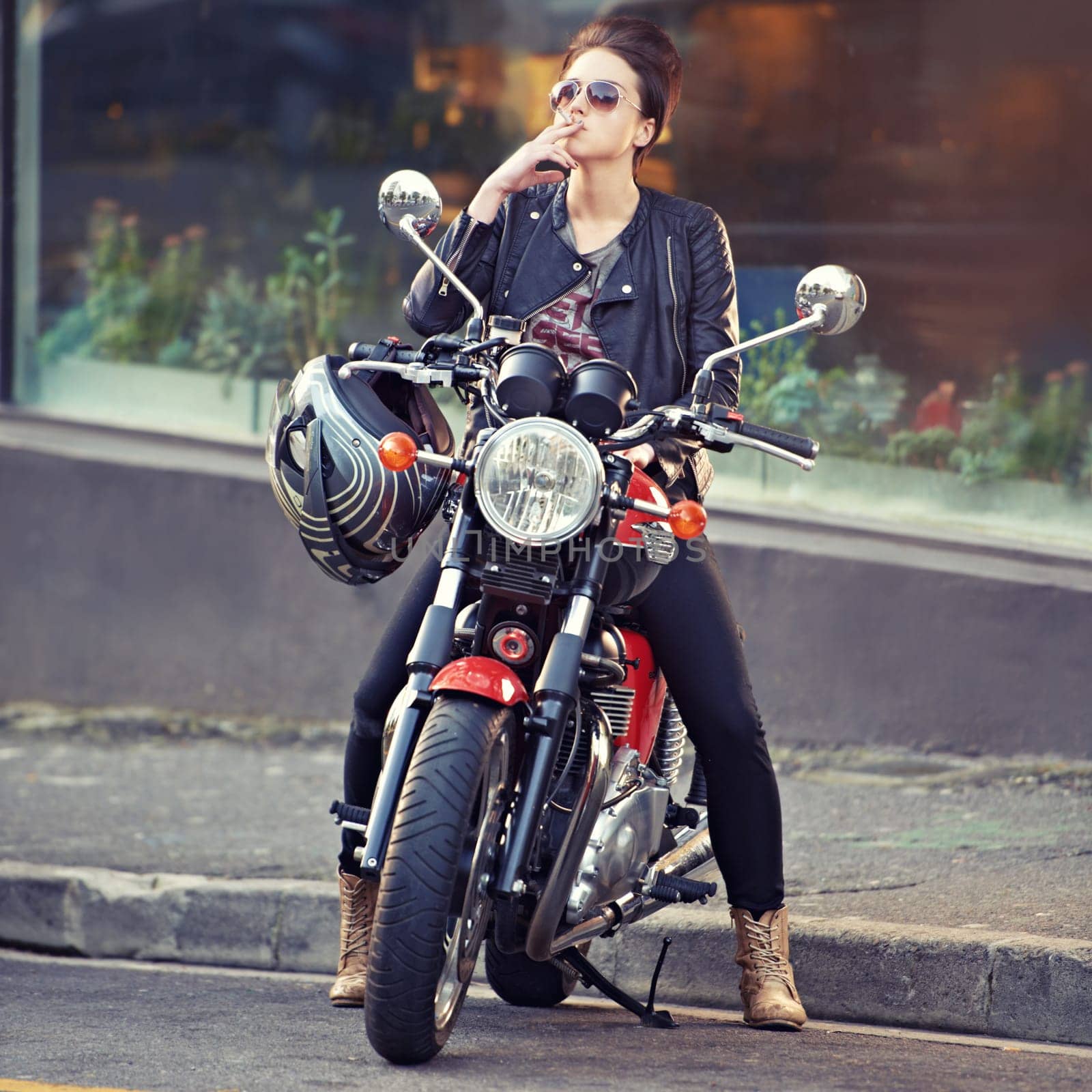 Motorcycle, leather and smoke with woman in city for travel, transport or road trip as rebel. Fashion, cigarette and sunglasses with model on classic or vintage bike for transportation or journey by YuriArcurs