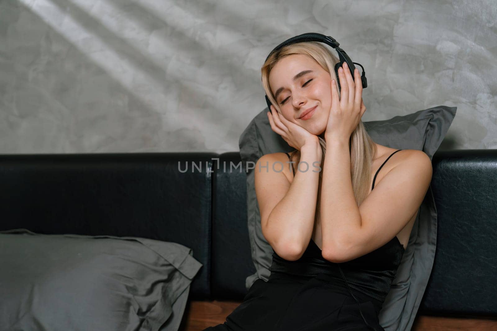 Young woman listening to music on headphone on her bed. Blithe by biancoblue