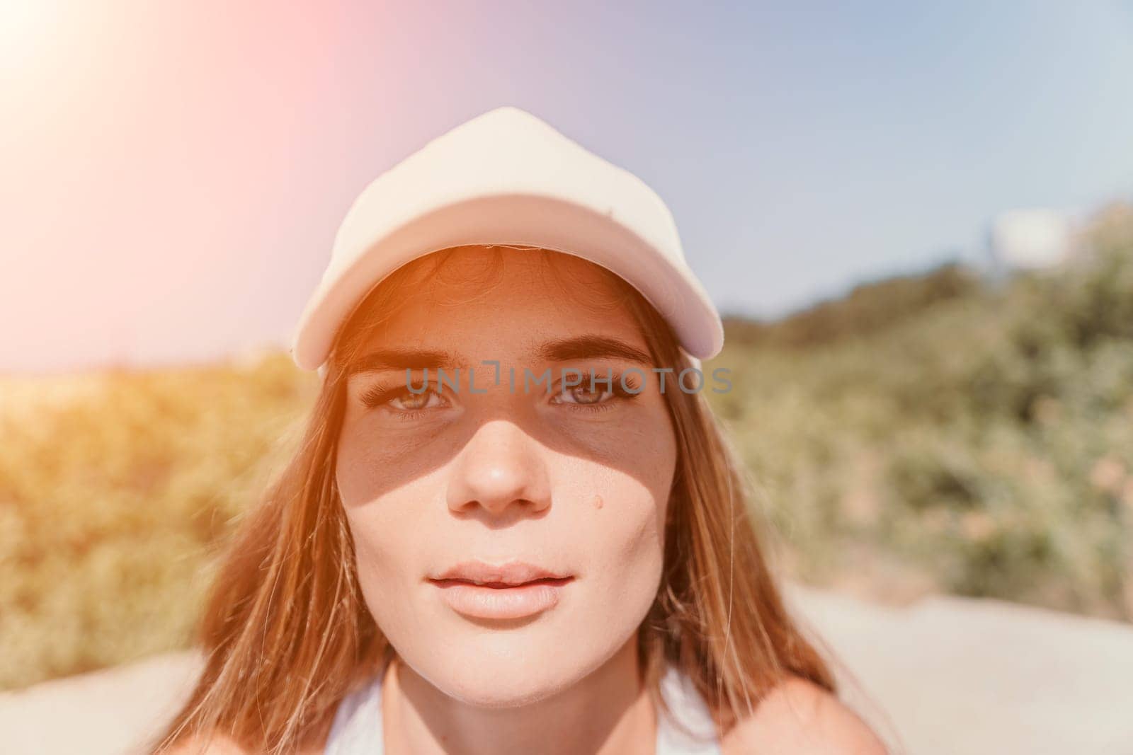 Woman travel sea. Happy tourist in hat enjoy taking picture outdoors for memories. Woman traveler posing on the beach at sea surrounded by volcanic mountains, sharing travel adventure journey by panophotograph