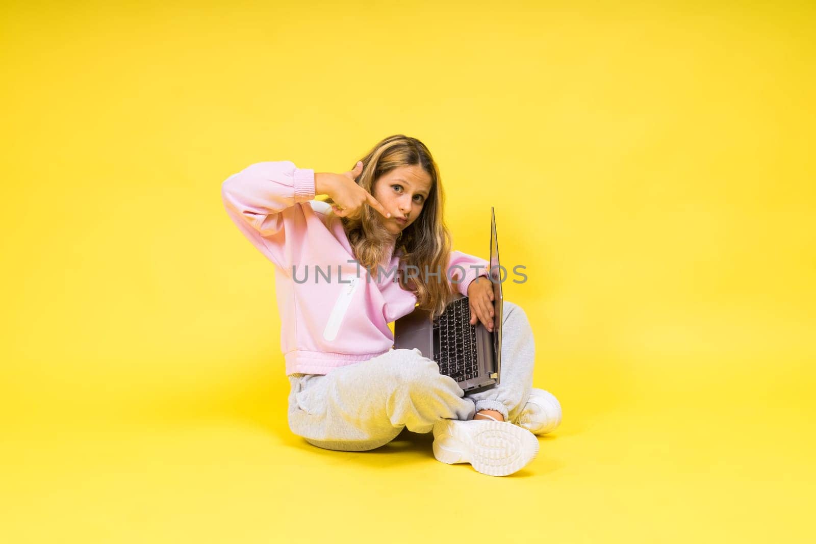 Teenager girl with notebok computer laptop sitting in a studio