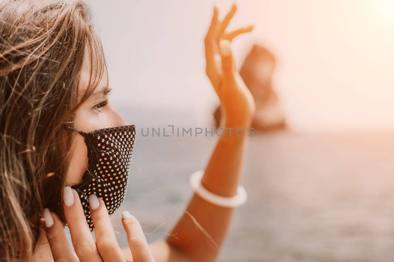 Woman summer travel sea. Happy tourist in black mask enjoy taking picture outdoors for memories. Woman traveler posing on the beach at sea surrounded by volcanic mountains, sharing travel adventure by panophotograph