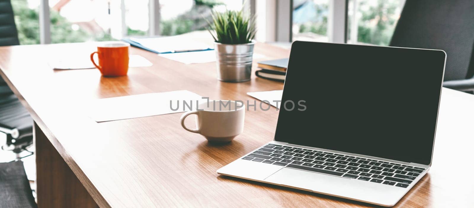 Laptop computer with opened lid on table in meeting room of office workspace. uds