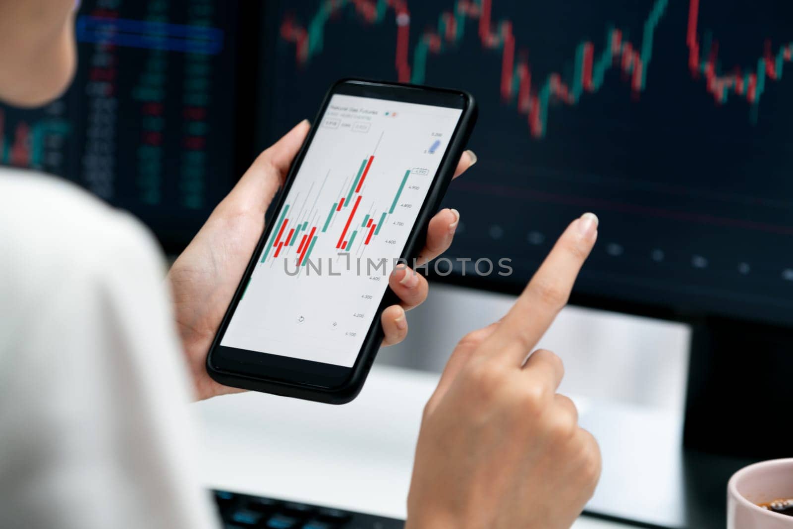 Cropped image in businesswoman using smartphone in profitable of exchange stock market graph comparing with pc screens at modern office. Concept of investing high profit in wealth security. Stratagem.