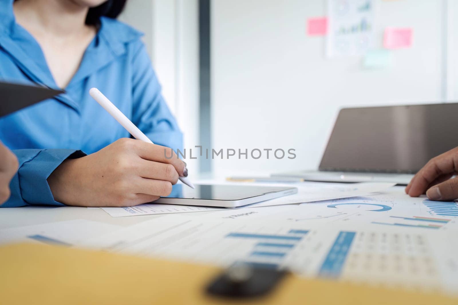 Businesswoman using tablet in meeting for brainstorming and discuss analysis of investment growth graph together.