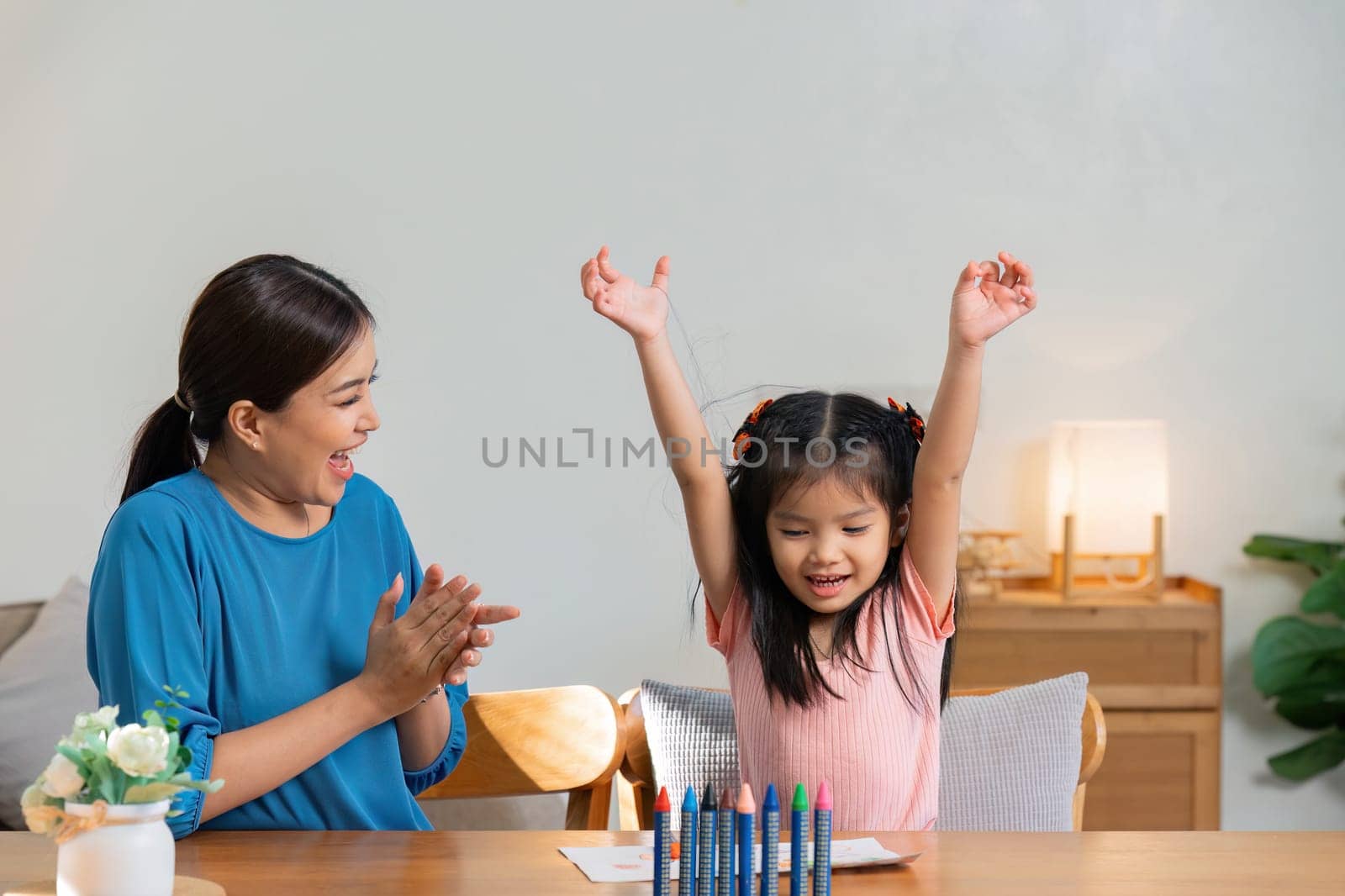 Happy family. Mother and daughter drawing together. Adult woman helping to child girl.