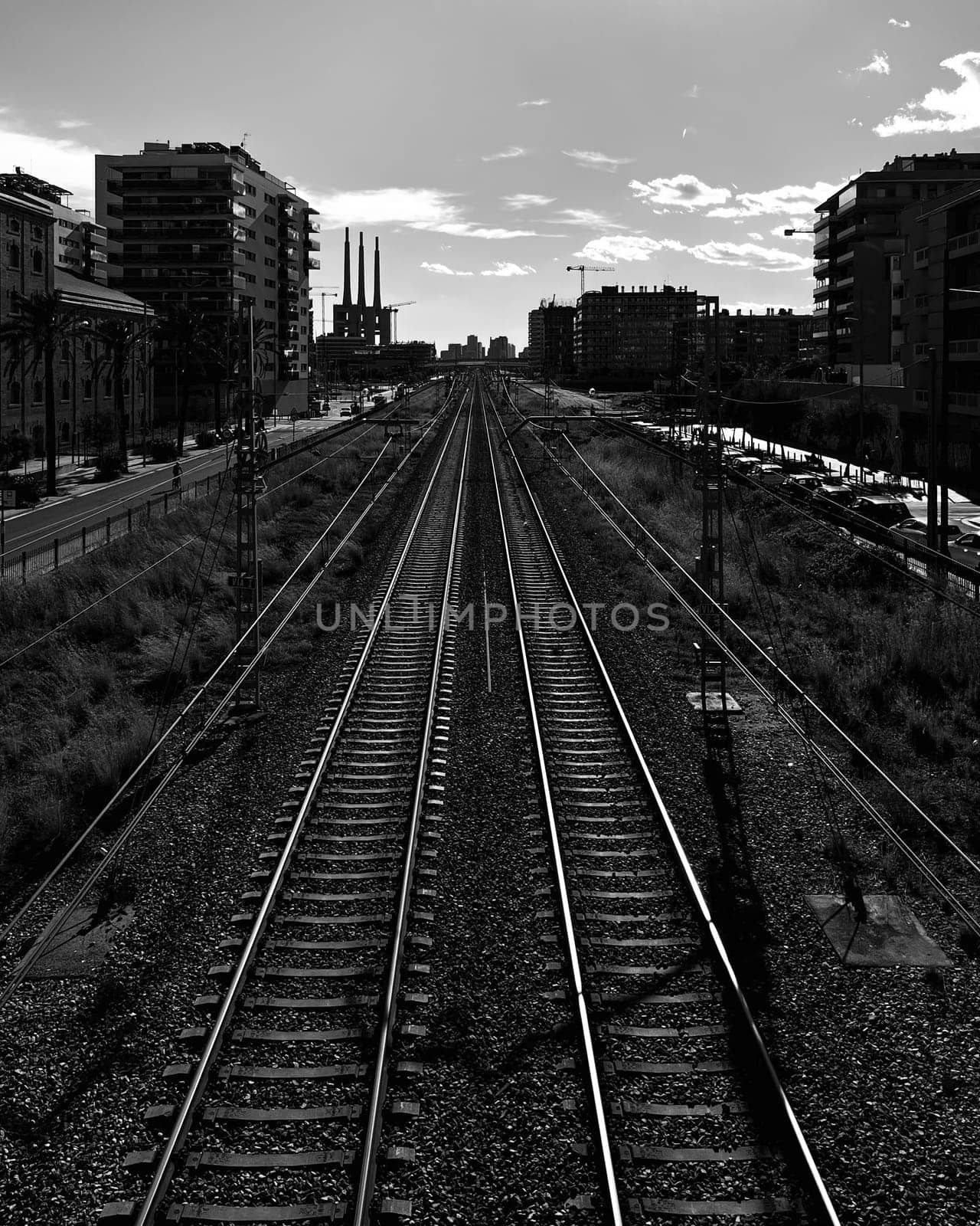 Railway tracks cutting through a city with buildings on both sides, under a cloudy sky