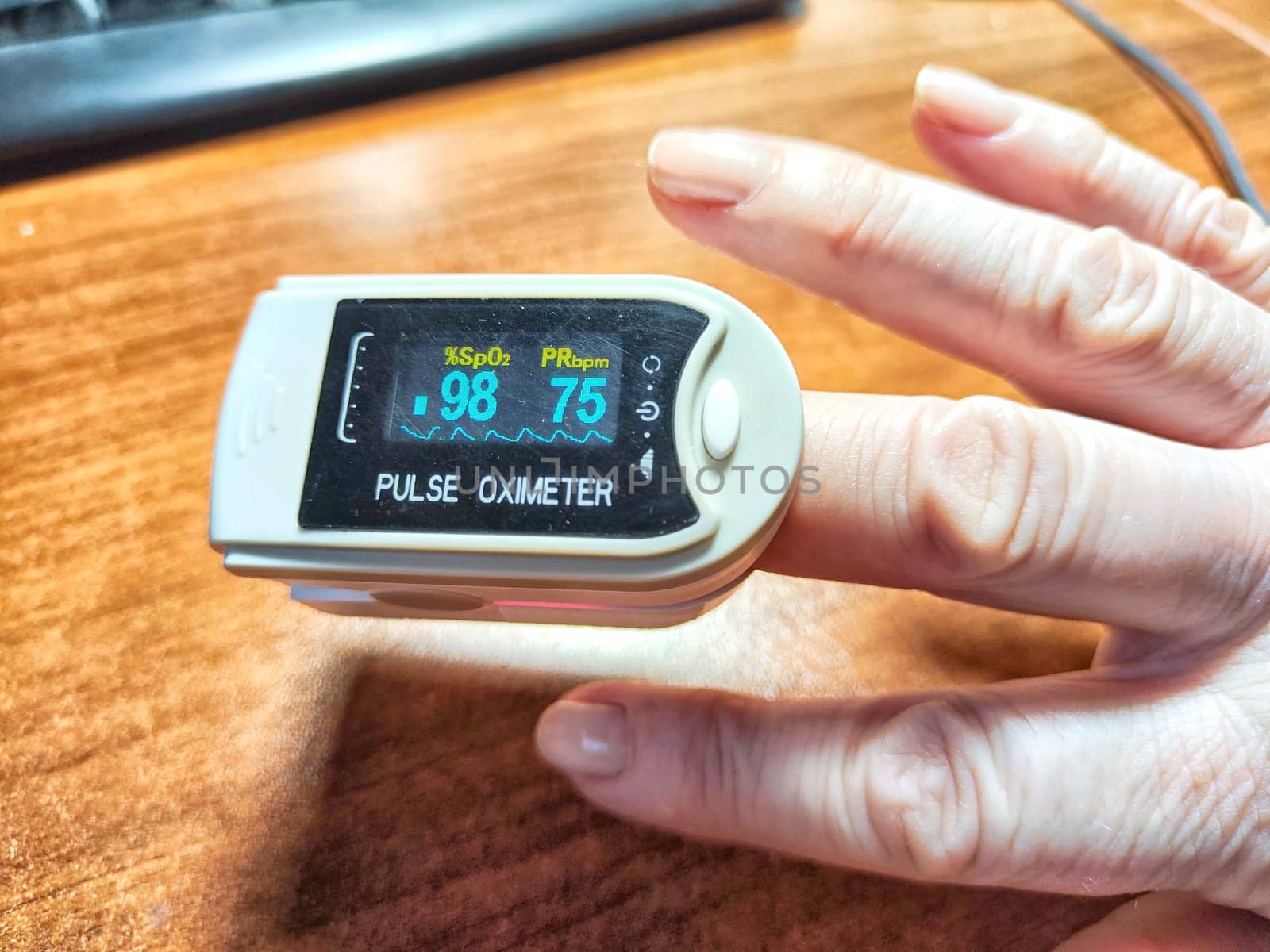 Close up of hand with a pulse oximeter on the finger.