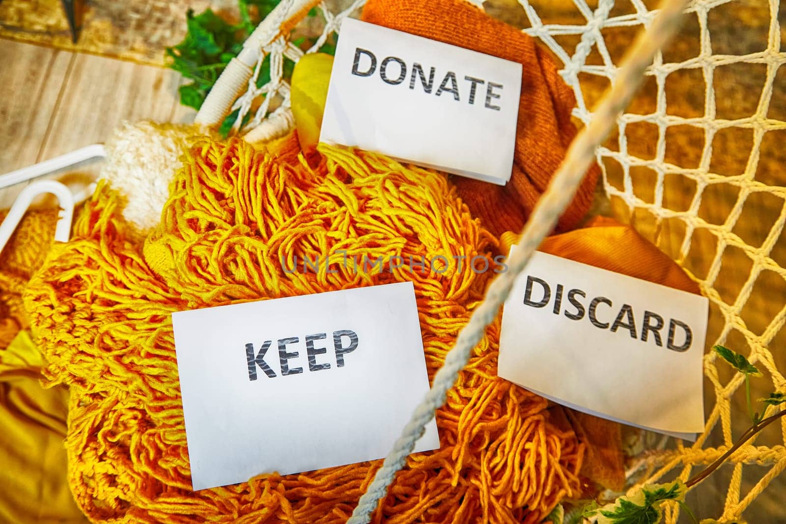 Signs with the words keep, donate, discard and fashion clothes folded in stacks in cozy room. The concept of cluttering and decluttering. Background