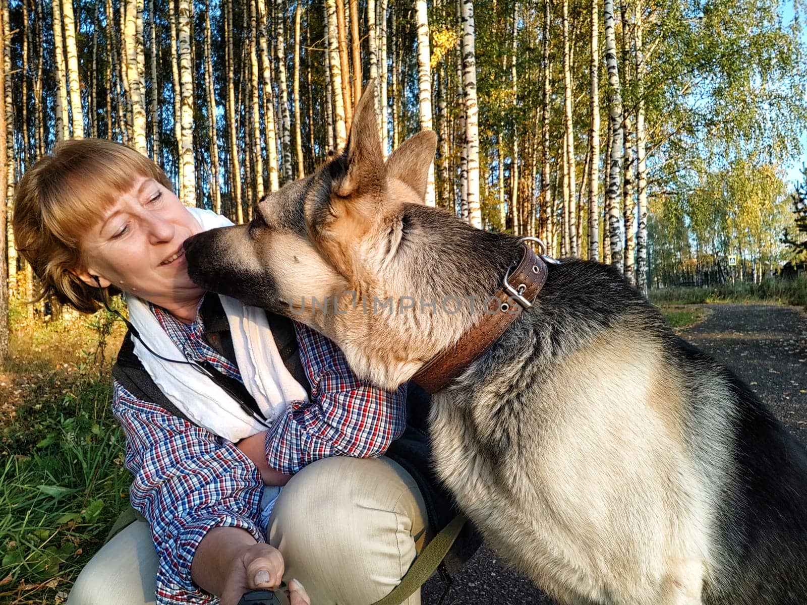 Adult girl with shepherd dog taking selfies in forest. Middle aged woman and big shepherd dog on nature. Friendship, love, communication, fun, hugs
