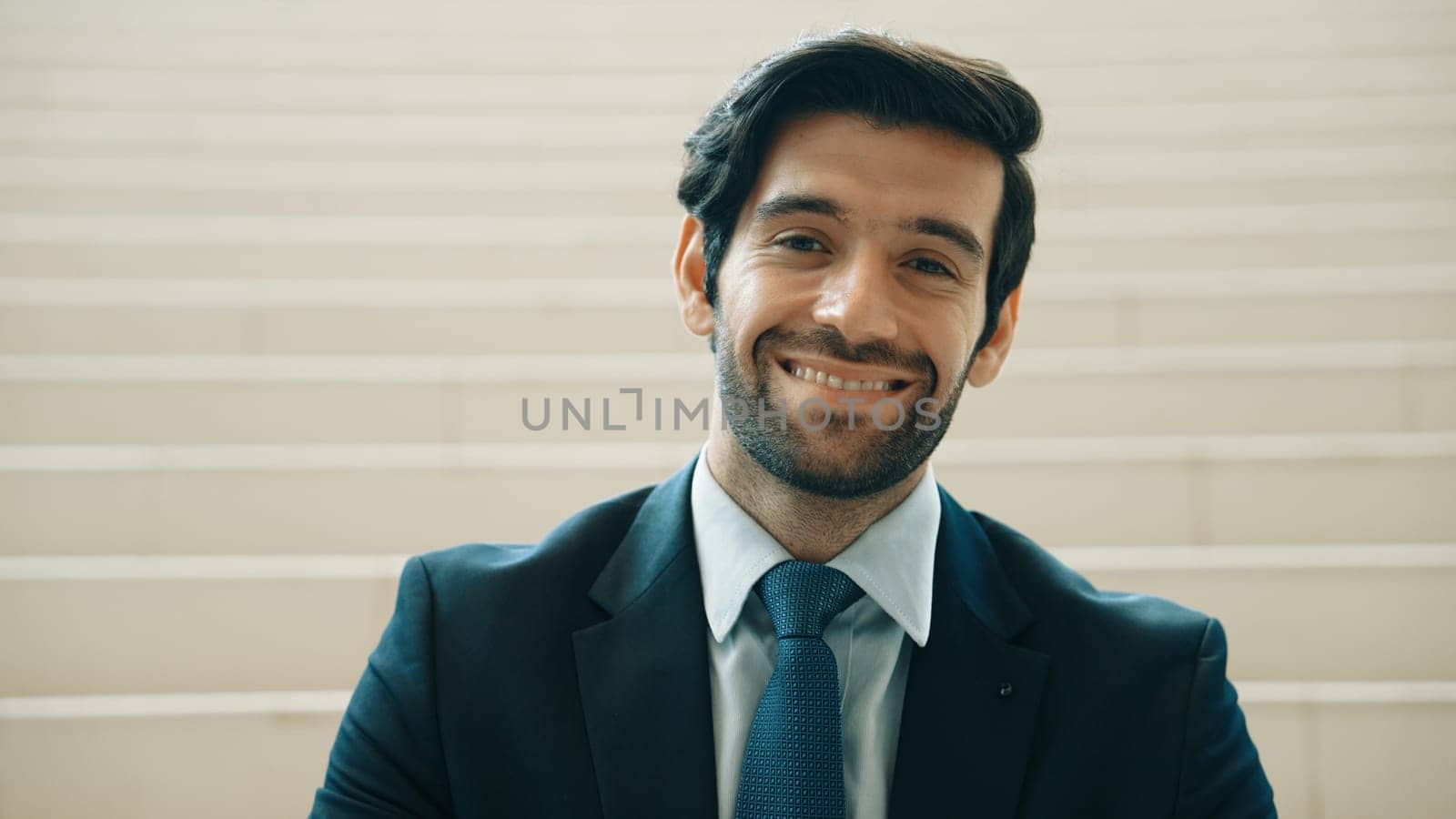 Portrait of smiling business man looking at camera while standing at stairs. Closeup of successful man smiling at camera while wearing business suit. Happy executive manager look at camera. Exultant.