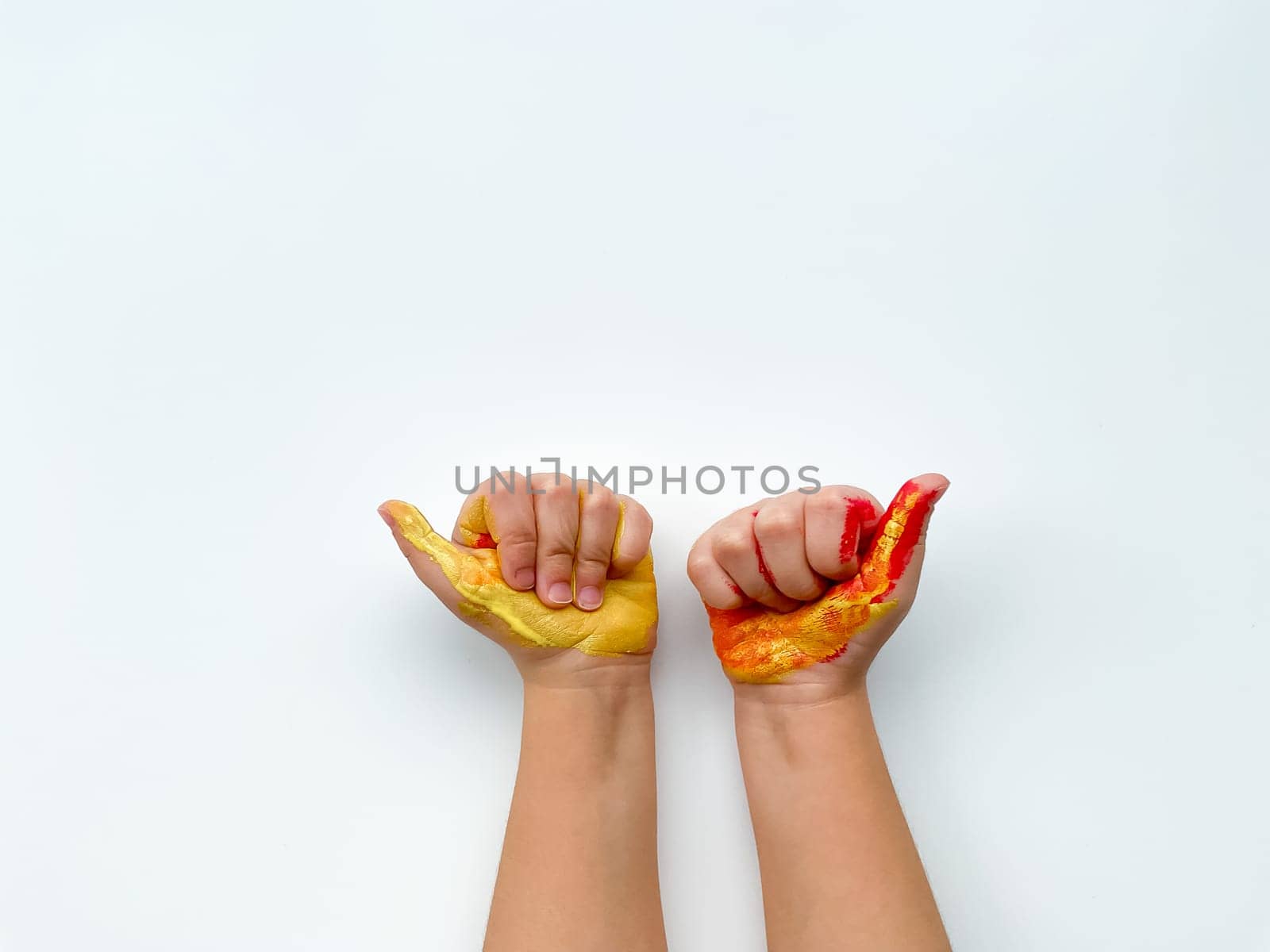 Childrens hands painted with yellow and red paint on white background. High quality photo