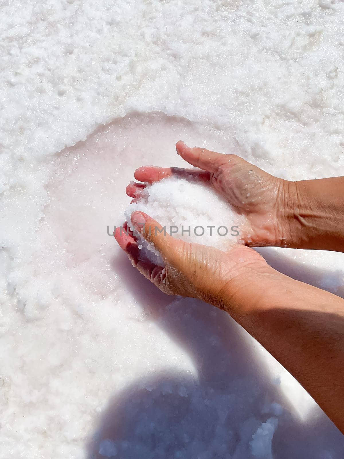 Womans hands with salt in her hands against the backdrop of salt lake. by Lunnica