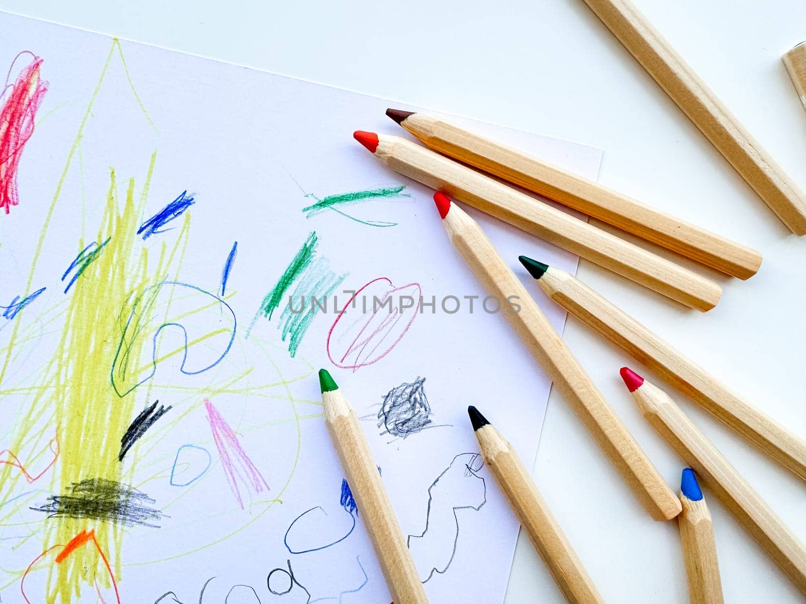 Colored pencils on the background of a childs drawing. Top view. by Lunnica