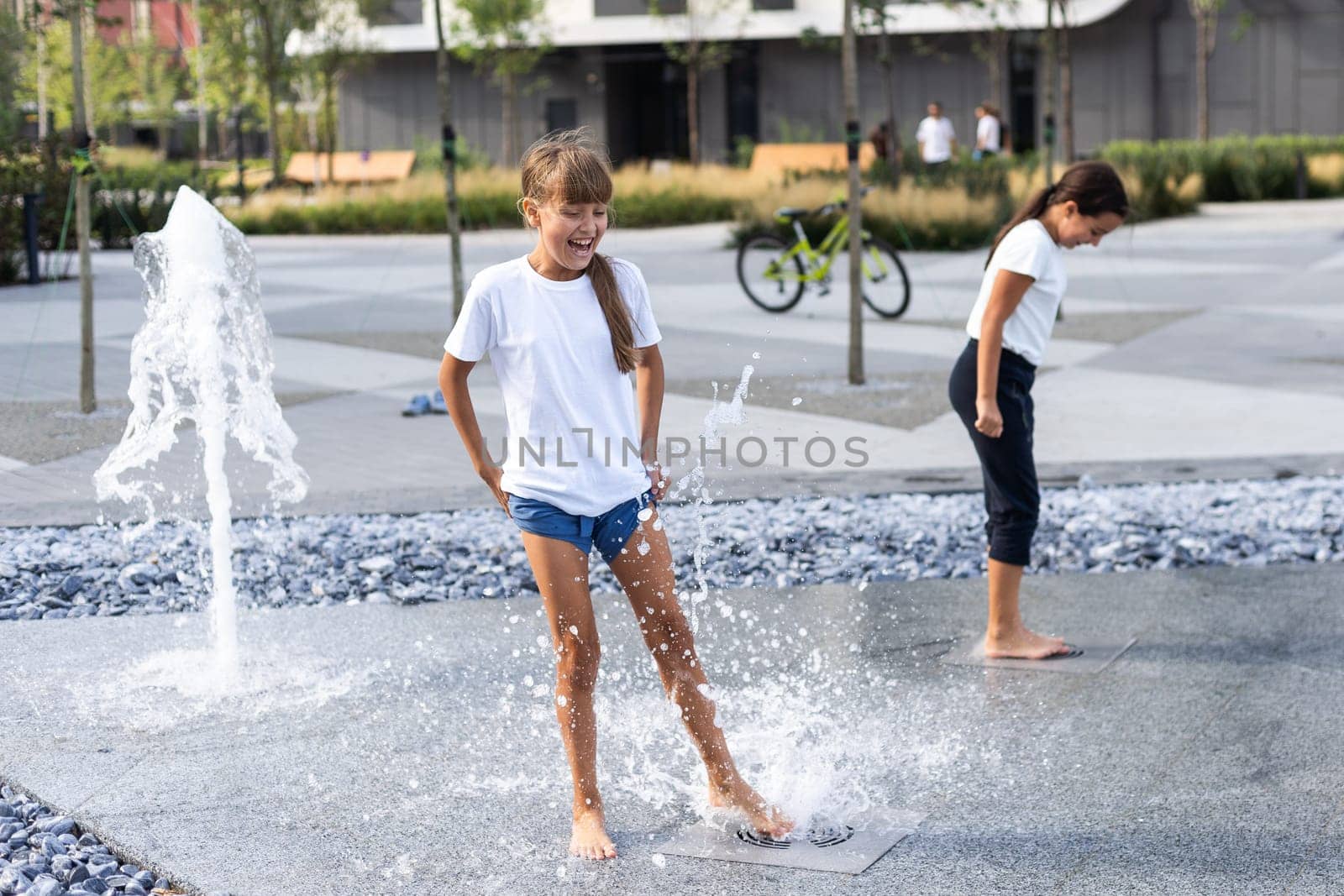 On a hot day, children run and have fun at the city fountain. Leisure time concept. summer holidays. happy childhood. by Andelov13