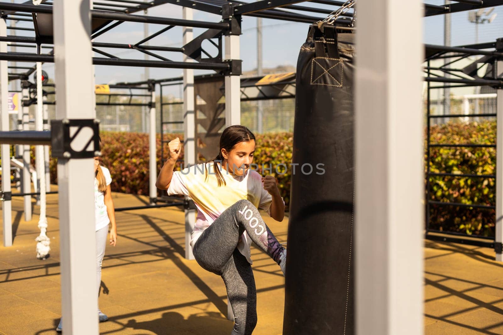 Young girl muay thai fighter working with the heavy bag by Andelov13