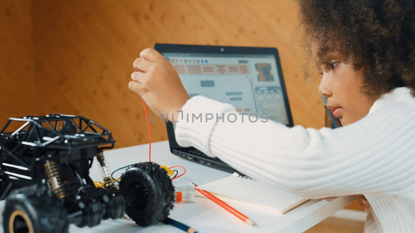 African girl build robotic car while using wires while using laptop. Erudition. by biancoblue