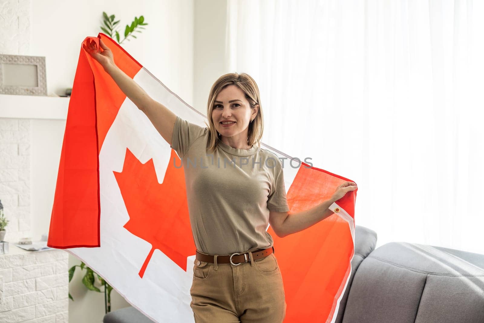 beautiful smiling woman covered in canadian flag looking at camera isolated on white by Andelov13