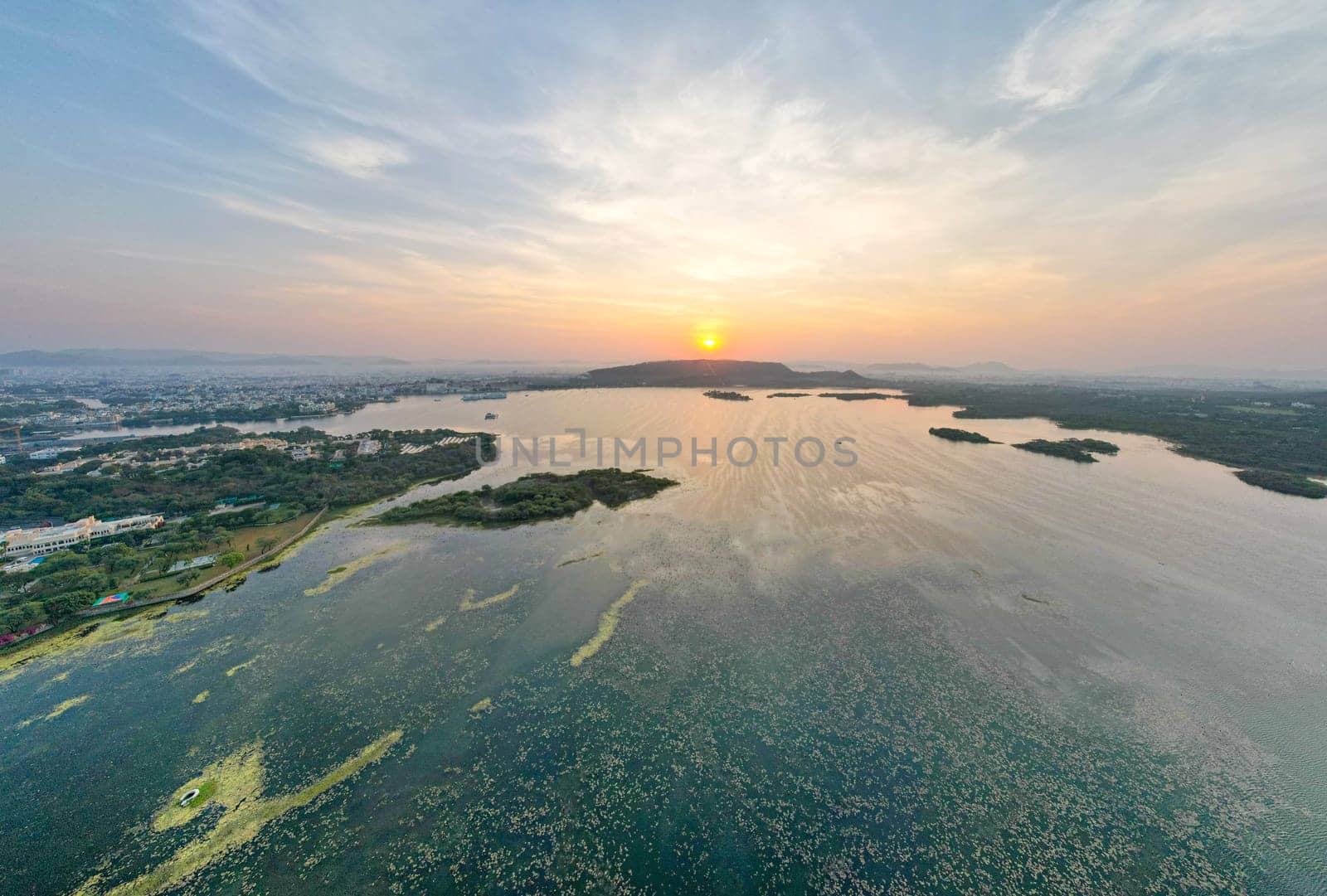 Aerial drone shot dawn dusk cityscape of Udiapur Rajasthan India with blue pink purple water of lake pichola fateh sagar towards aravalli mountains on foggy morning in India