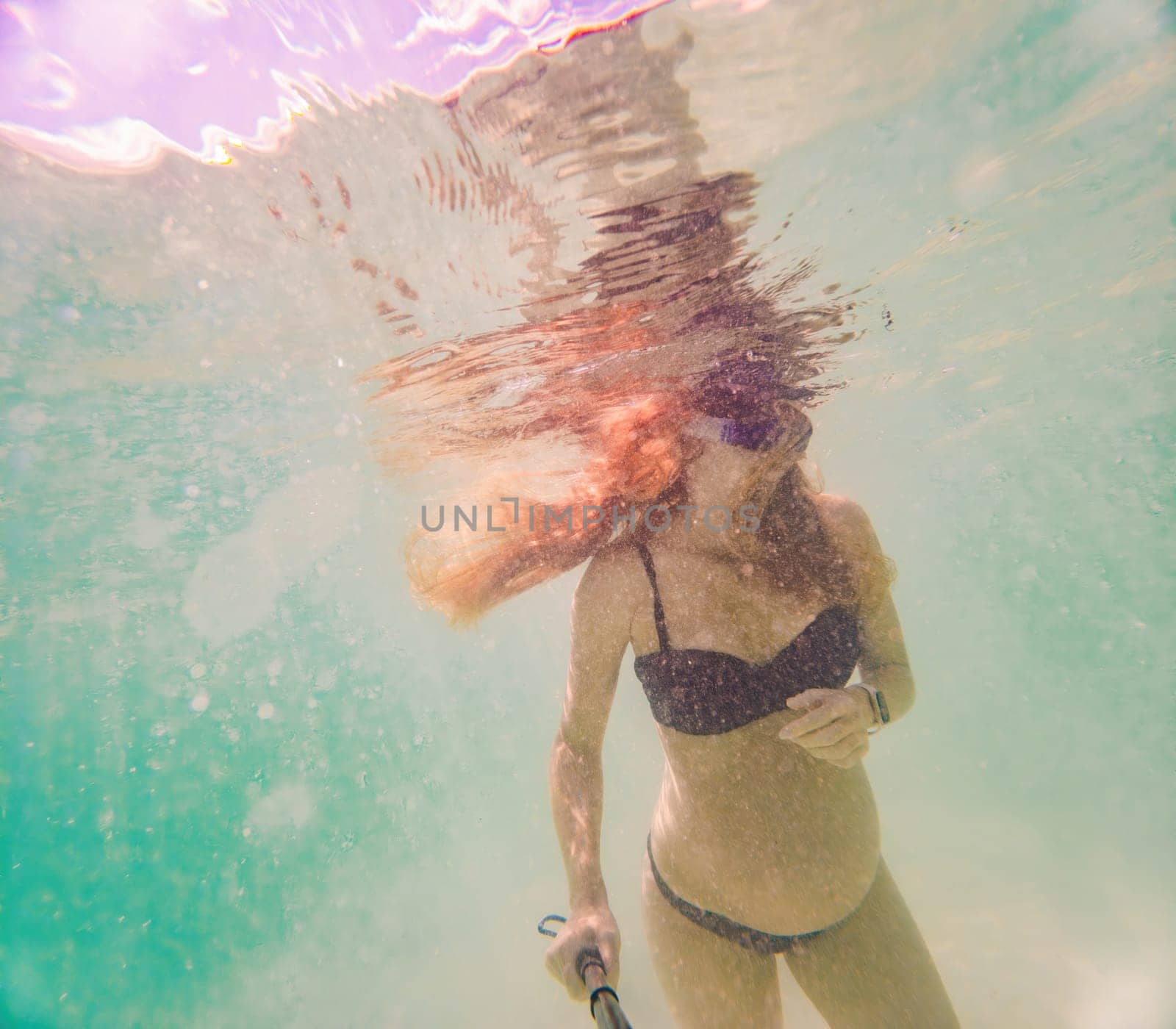 In an ethereal underwater scene, a pregnant woman gracefully floats, embodying the beauty of maternity beneath the tranquil surface of the sea.