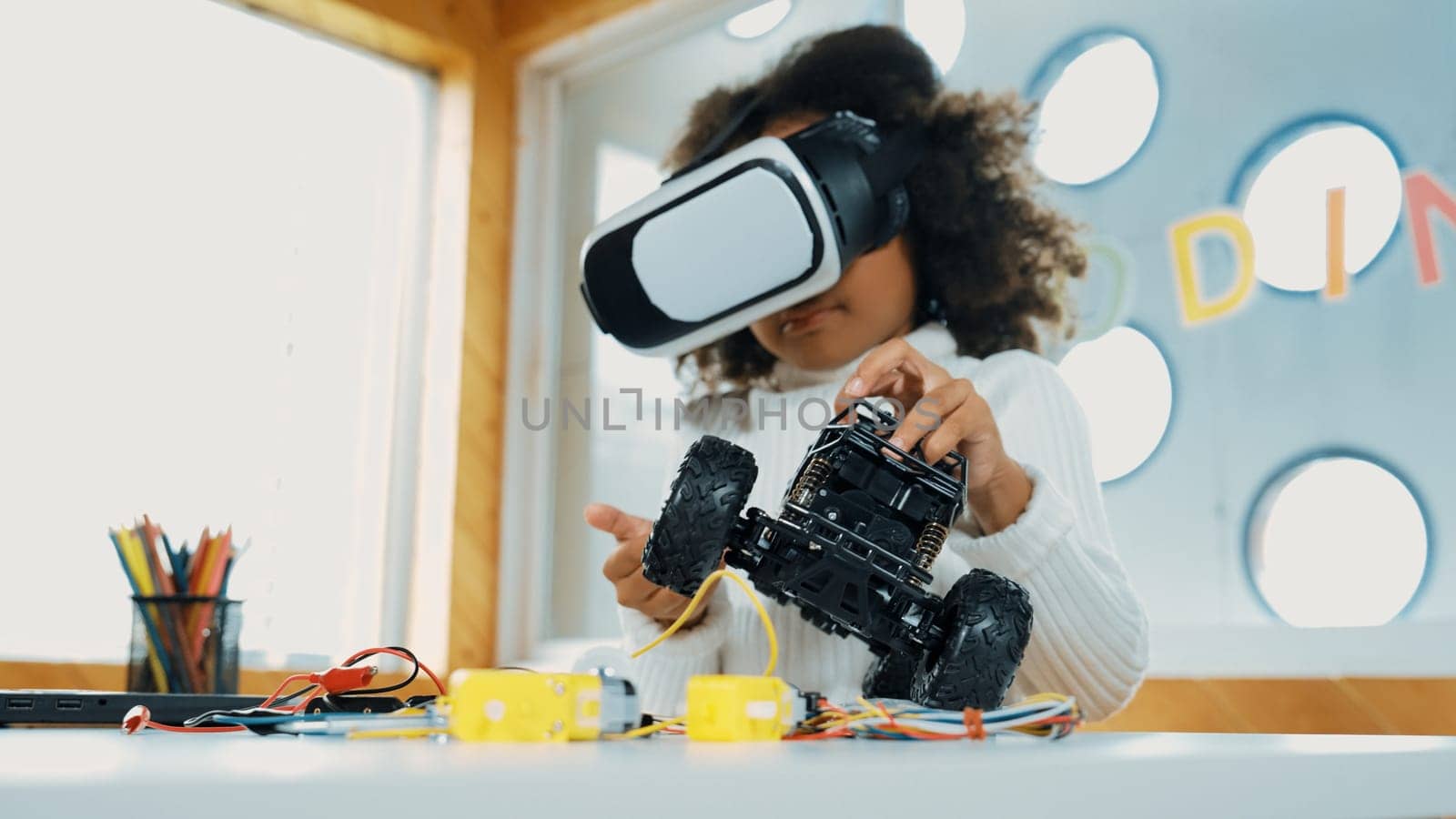 Smart african girl wearing VR vision glasses while hold car model. Student study visual reality and holding robotic model. Child using technology gadget in online education in STEM class.Erudition.