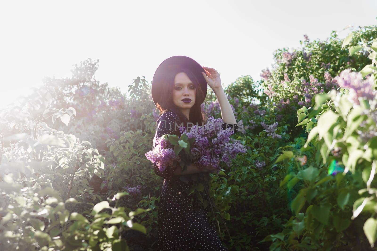 A fashionable girl with dark hair, a spring portrait in lilac tones in summer. Bright professional makeup