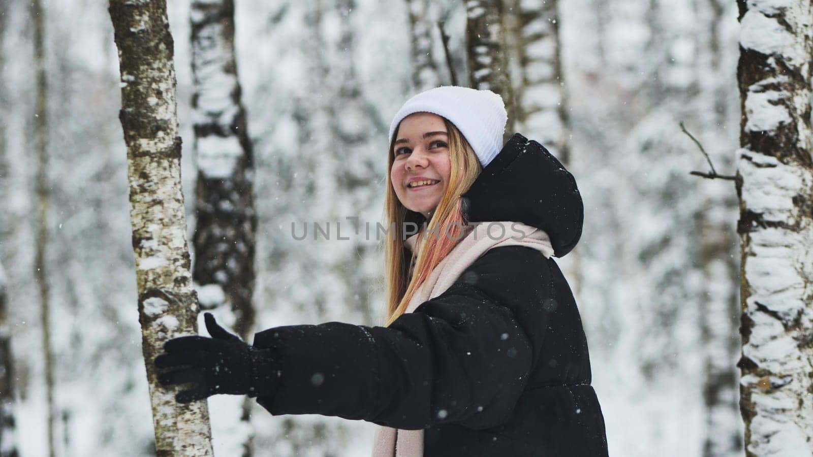 A girl walking in the forest in winter among the birches