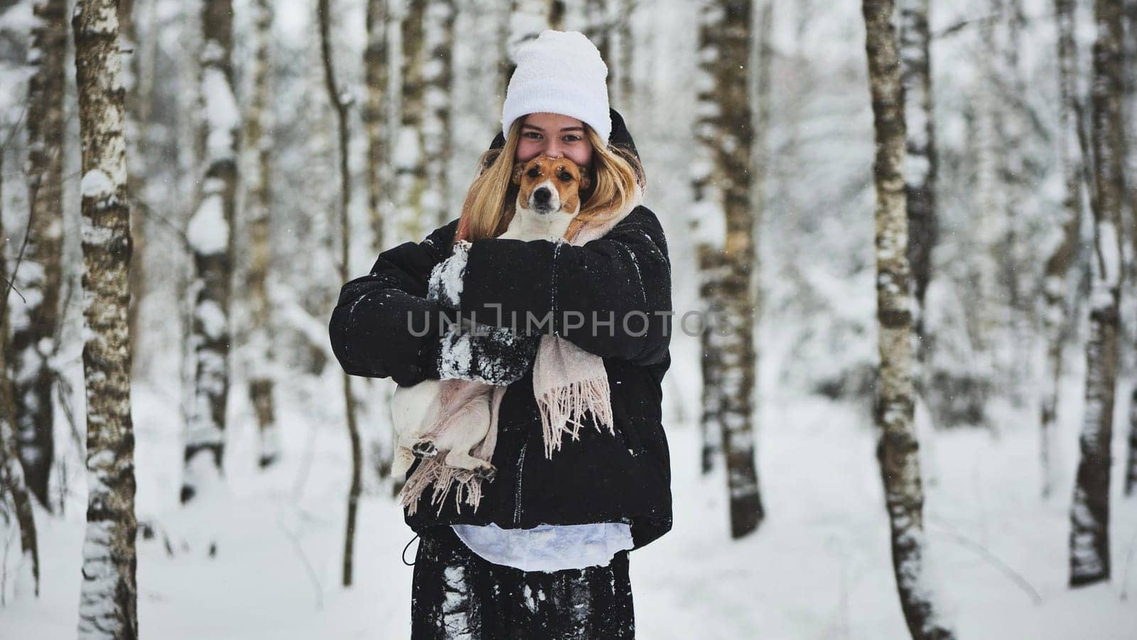 A girl cuddles a Jack Russell Terrier dog in the woods in winter