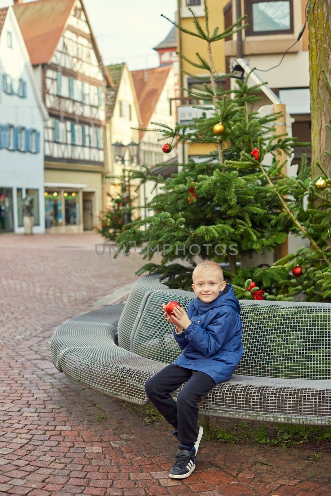 Winter Wonderland Delight: 8-Year-Old Boy with Christmas Decor by Vintage Fountain. by Andrii_Ko