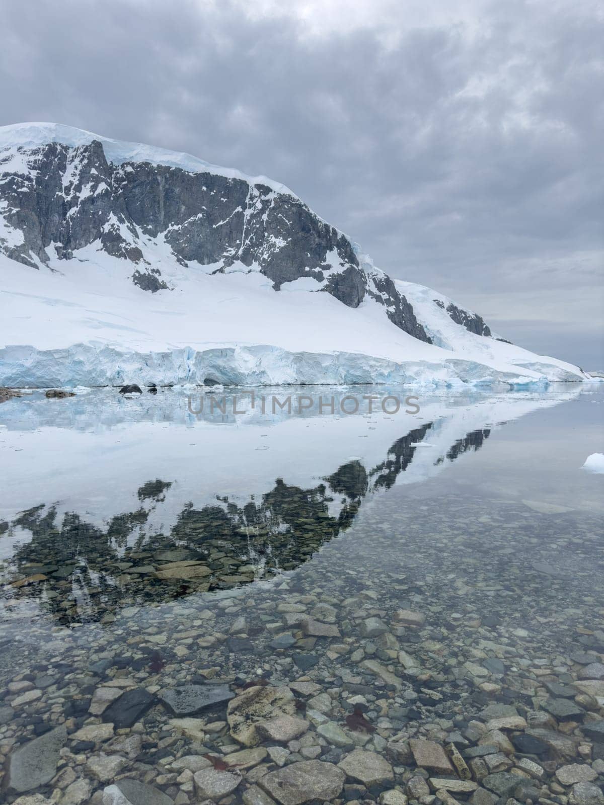 A huge high breakaway glacier in the southern ocean off the coast of Antarctica, the Antarctic Peninsula, the Southern Arctic Circle, azure water, cloudy weather. High quality photo