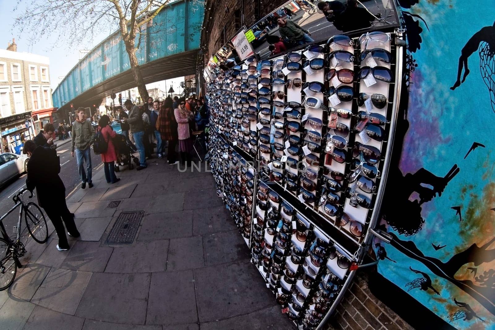 London, United Kingdom - April 01, 2007: Various sunglasses on display at street stall on Camden Market, famous flea market in UK capital, group of pedestrians in background. Fisheye photo