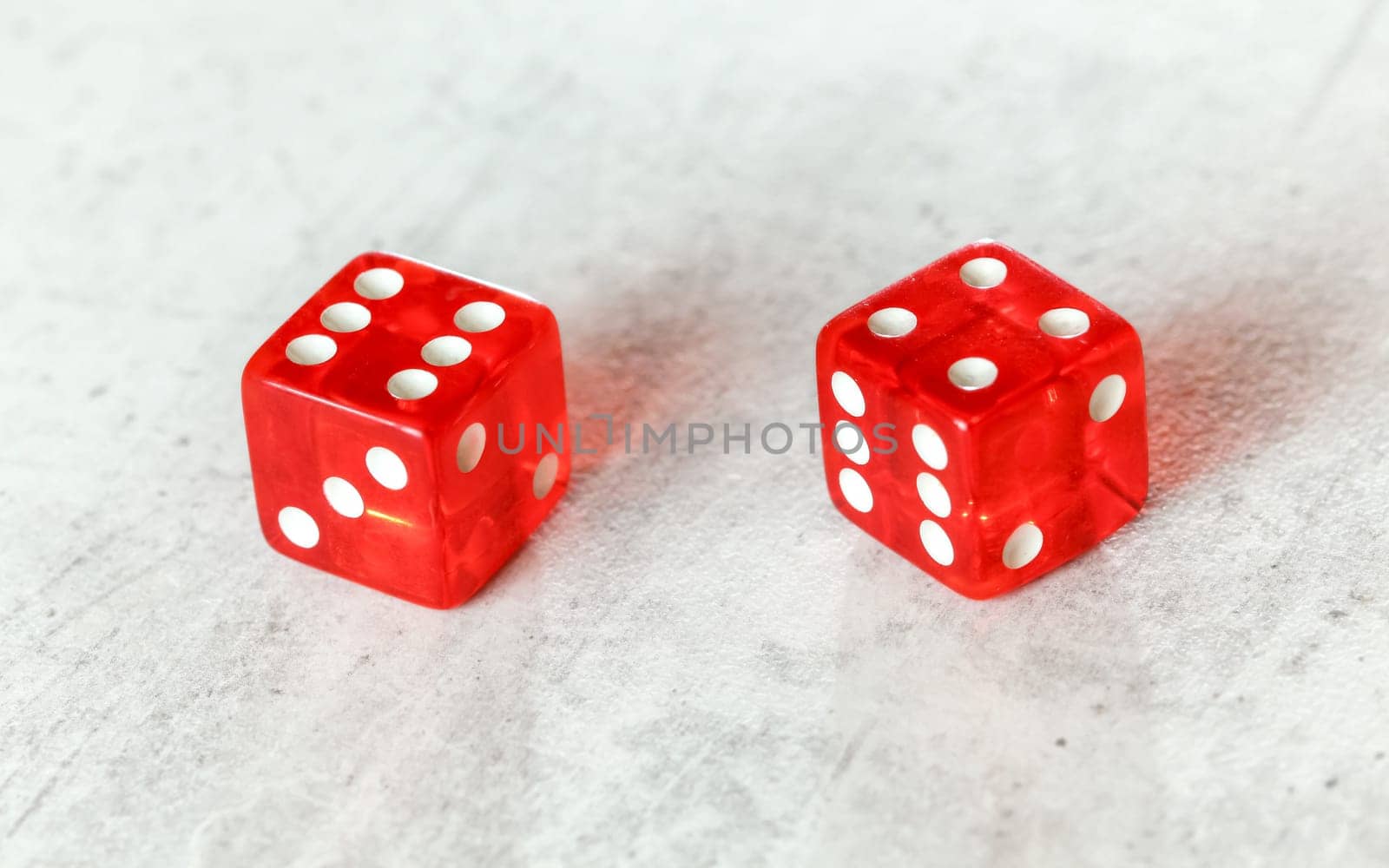 Two translucent red craps dices on white board showing Easy Ten (number 6 and 4) by Ivanko