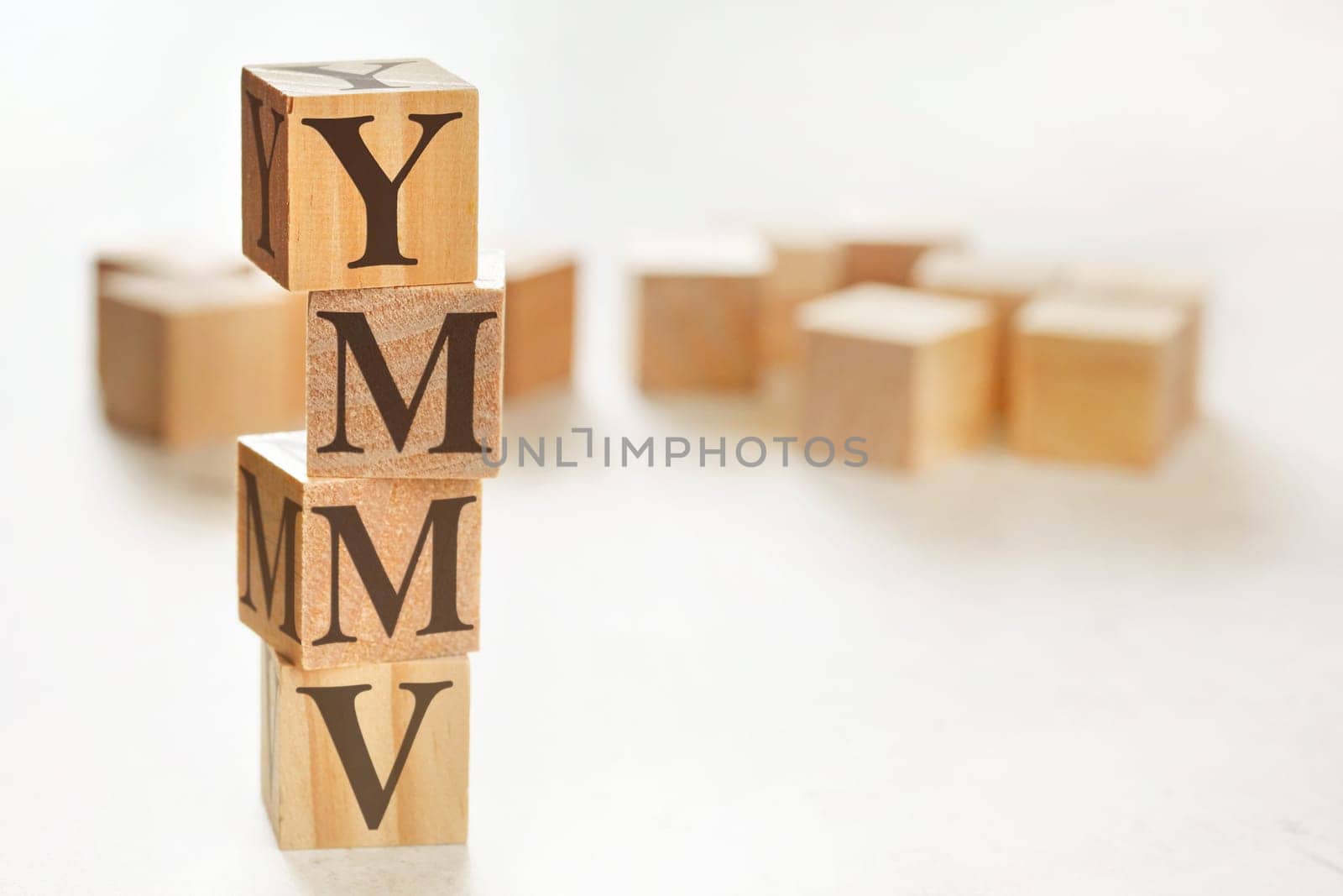 Four wooden cubes arranged in stack with letters YMMV (meaning Your mileage may vary) on them, space for text / image at down right corner