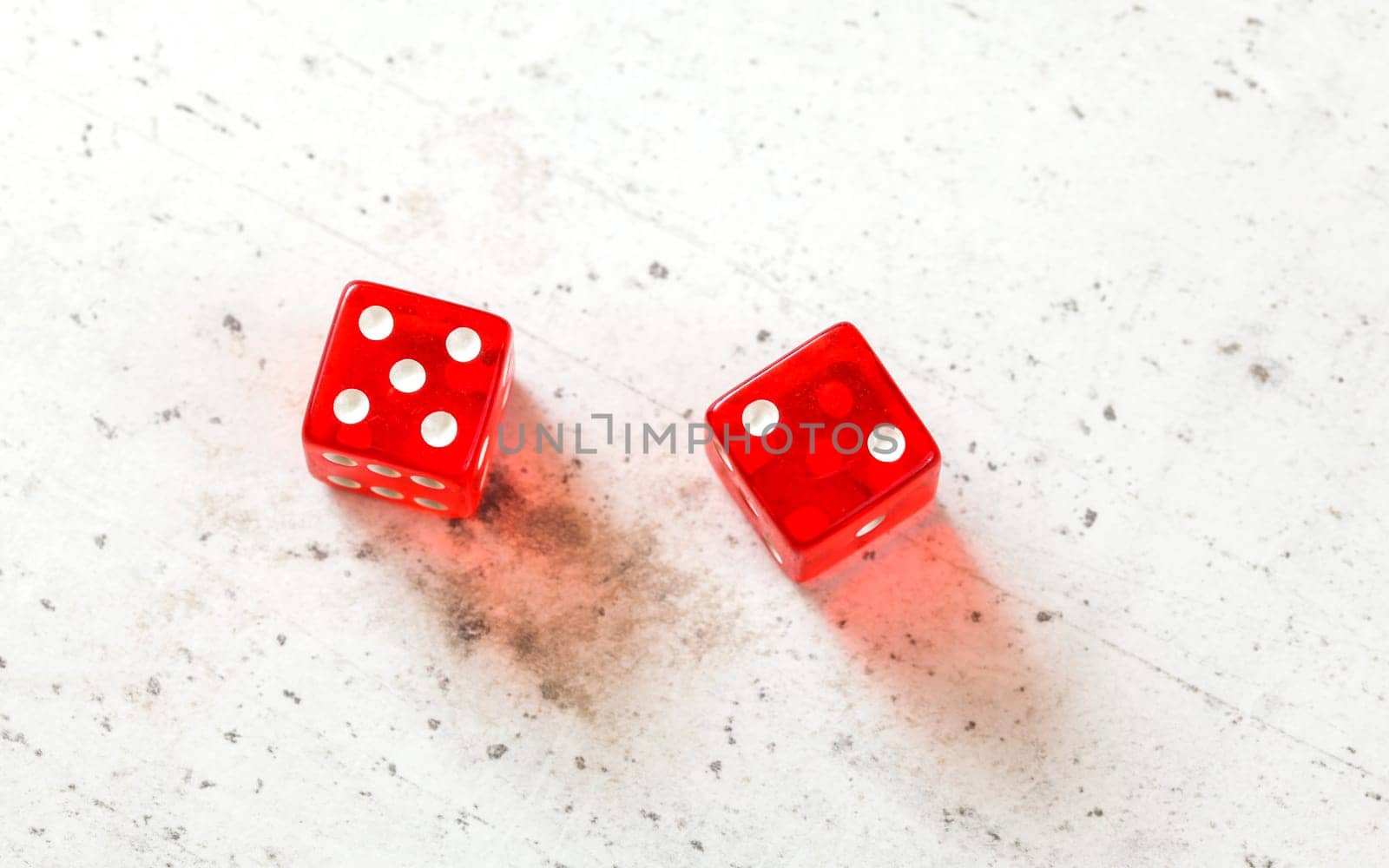 Two red craps dices showing Natural or Seven Out (number 5 and 2) overhead shot on white board by Ivanko