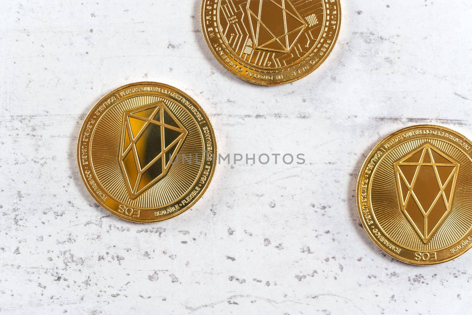 Top down view, golden commemorative EOS - EOSIO  cryptocurrency - coins on white stone board by Ivanko