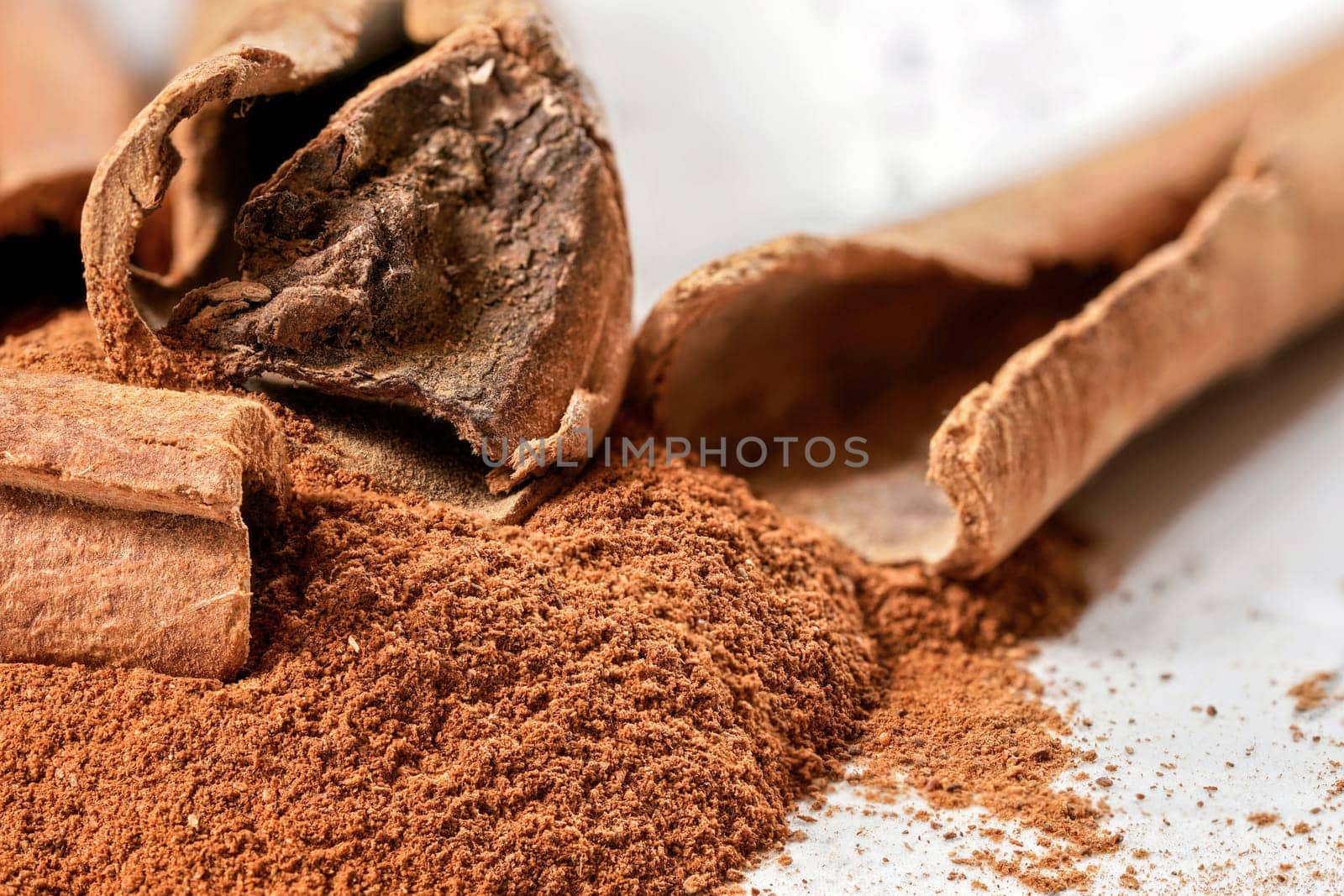 Closeup detail - Organic cinnamon bark stick and pile of grounded powder by Ivanko