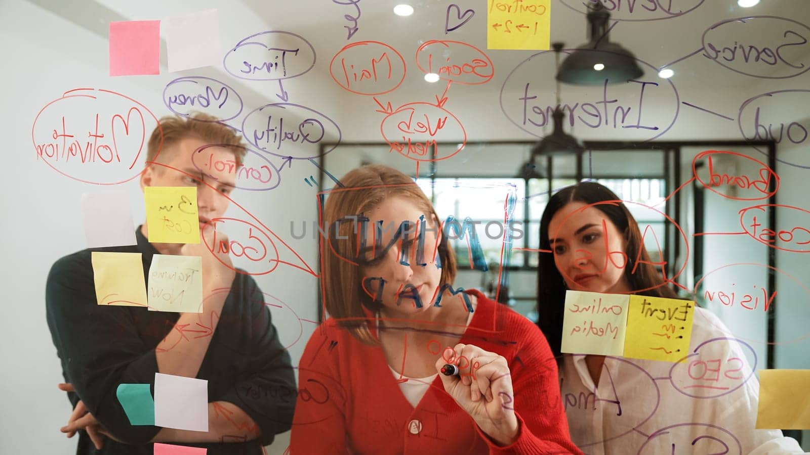 Creative business team brainstorming and sharing marketing idea about start up project by writing down on colorful sticky note at glass board modern meeting room. Working together. Immaculate.