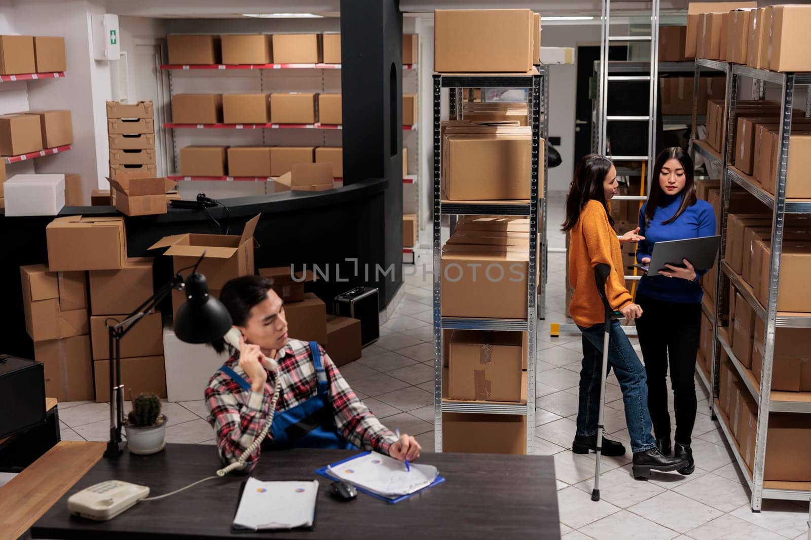 Delivery operators managing warehouse product audit in storage room. Retail industry storehouse employees working together, tracking parcel transportation online on laptop