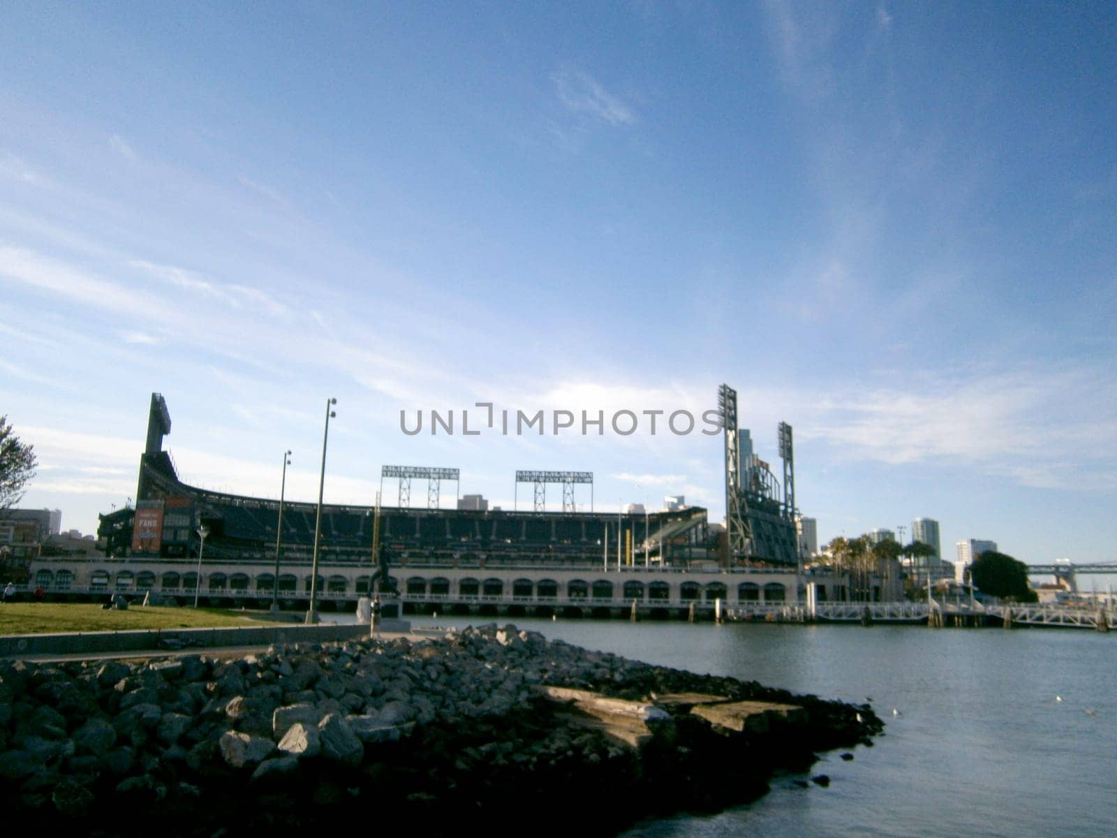 San Francisco - October 9, 2011: Clear view of Oracle Park, home to the San Francisco Giants, from across McCovey Cove. The photo shows the calm waters of the cove reflecting the sky, and the rocky shoreline at the bottom. The photo also shows the distinctive architecture and stadium lights of Oracle Park. 