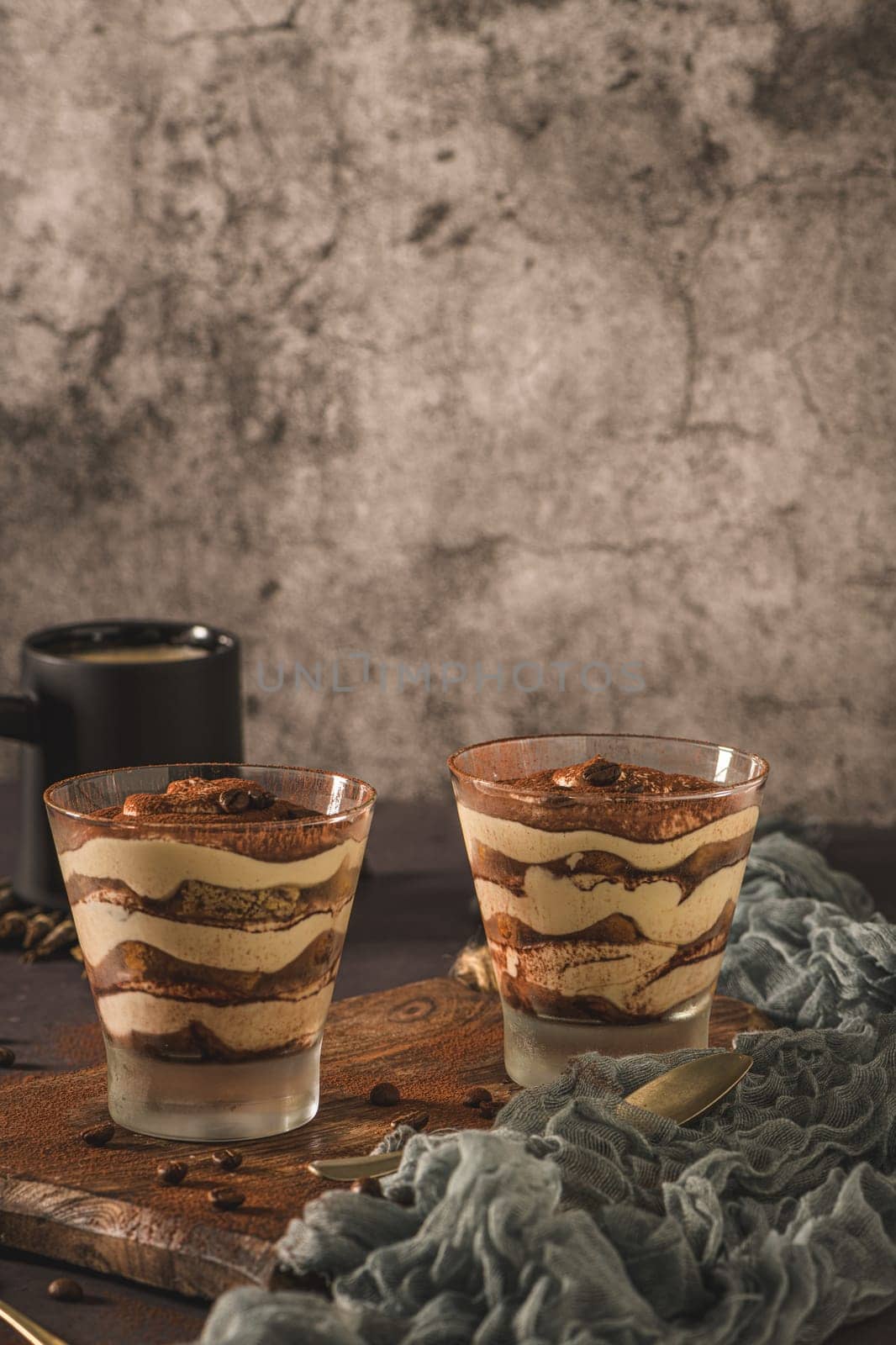 Delicious italian dessert tiramisu in a glasses on a dark slate, stone or concrete background.