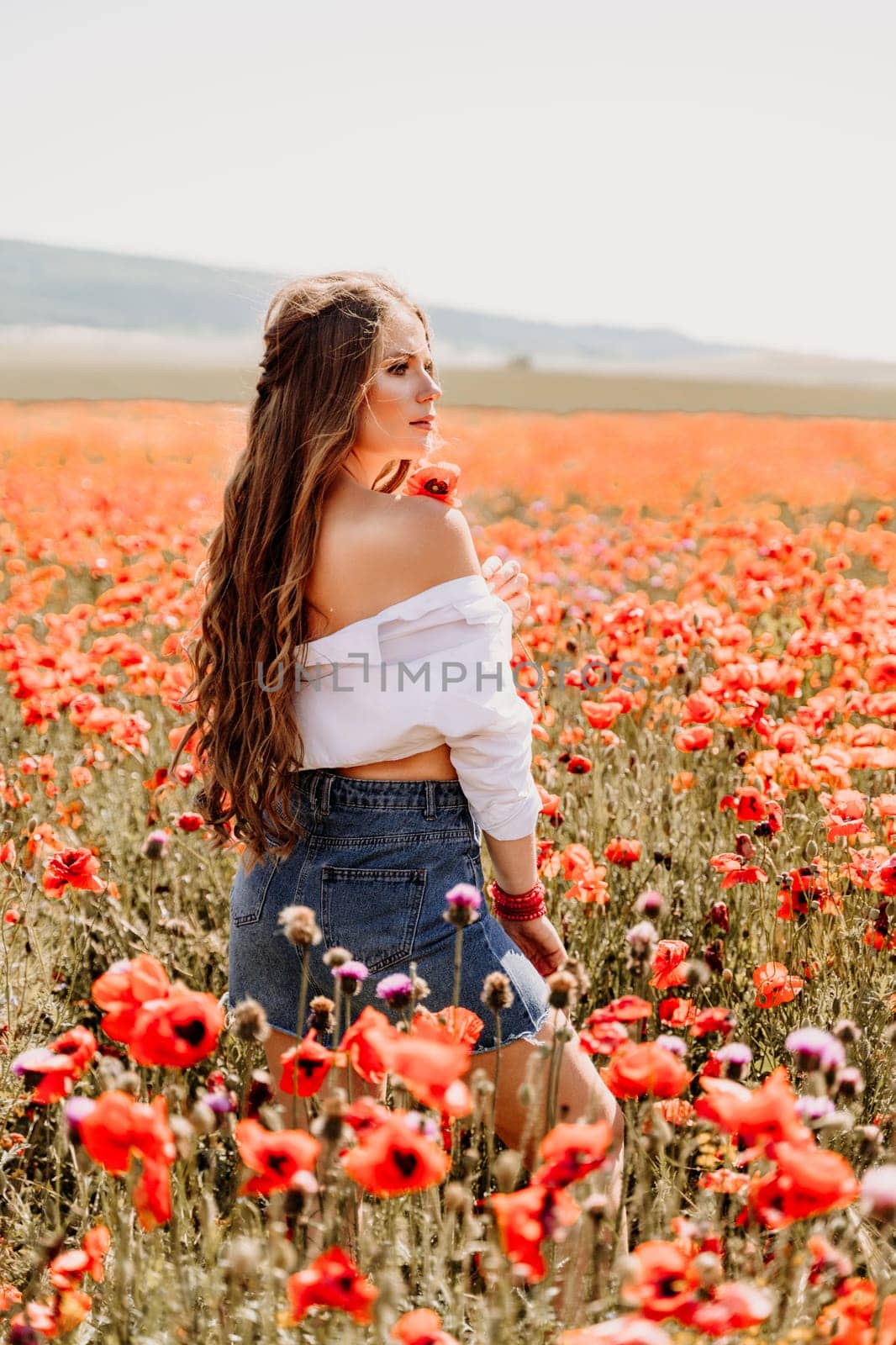 Woman poppies field. Side view of a happy woman with long hair in a poppy field and enjoying the beauty of nature in a warm summer day. by Matiunina