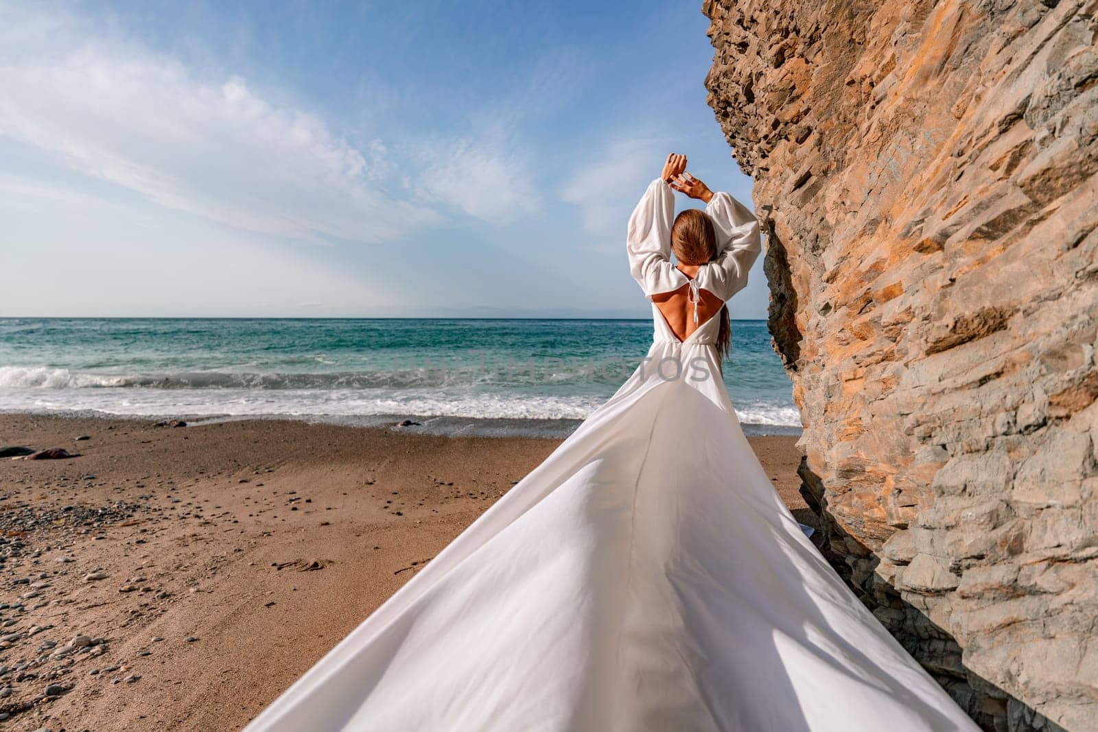 Woman beach white dress flying on Wind. Summer Vacation. A happy woman takes vacation photos to send to friends. by Matiunina