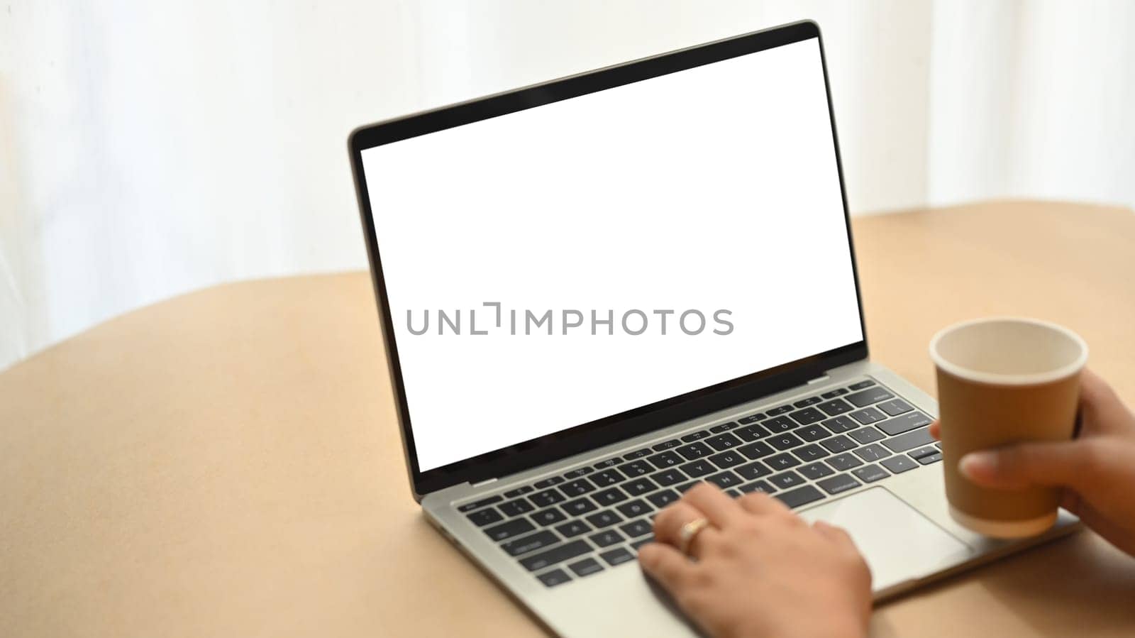 Businesswoman holding paper cup and working with laptop. Closeup view