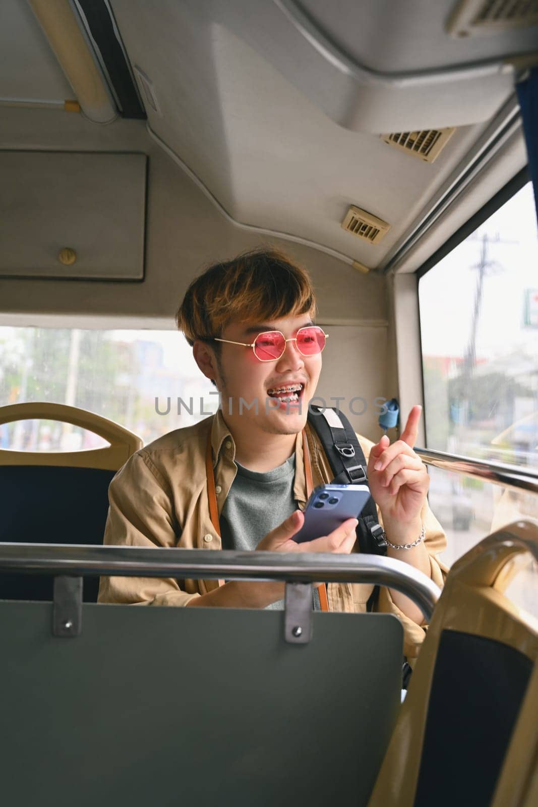 Young stylish man text messaging on smart phone, traveling by bus. Public transportation concept by prathanchorruangsak