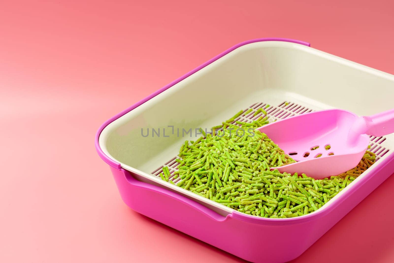 Pet litter box with bio filler on pink background close up